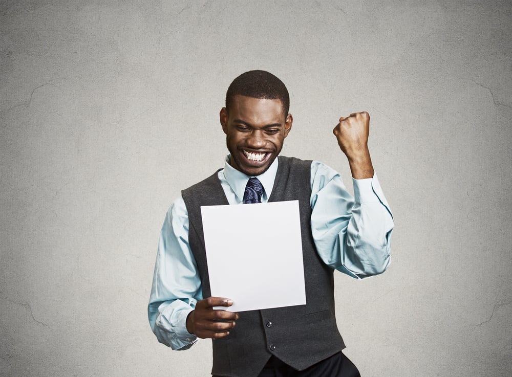 Closeup portrait happy excited young business man executive looking monthly statement glad to pay off bills isolated grey background. Positive emotion facial expression. Financial success good news Closeup portrait happy excited young business man executive looking monthly statement glad to pay off bills isolated grey background. Positive emotion facial expression. Financial success good news